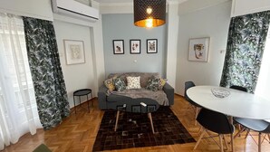 Una sala de estar moderna con un sofá gris, una mesa redonda y una lámpara colgante.