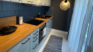 Una cocina moderna con encimera de madera, pileta de acero inoxidable y horno empotrado.
