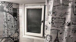 Baño con inodoro, lavamanos y cortina de ducha con diseños parisinos.