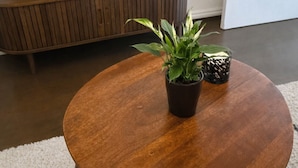A round wooden coffee table with a potted plant and a candle in a glass holder. - Classic Comfort in the Heart of Monastiraki | Walk to the Acropolis, Agora & More (Athina)
