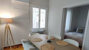 A dining area with a wooden table, white chairs, and a standing lamp. - Elegant Kolonaki Retreat | Sophisticated 2-Bedroom Apartment in Upscale Central Athens (Athina)