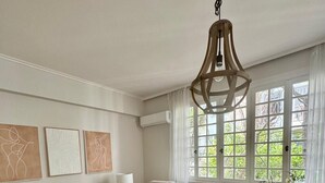 A modern living room with a beige sofa, a coffee table, and a hanging light fixture. - Elegant Kolonaki Retreat | Sophisticated 2-Bedroom Apartment in Upscale Central Athens (Athina)