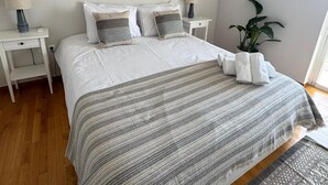 A neatly arranged bedroom with a large bed, two bedside tables, a potted plant, and wall art. - Sunset Sea View Pangrati Flat (Athina)