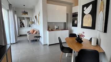A modern kitchen with white cabinets, a dining area with a wooden table and black chairs, and artwork on the walls.