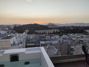 Una terraza en la azotea con vistas a un paisaje urbano, incluyendo edificios y una colina distante.