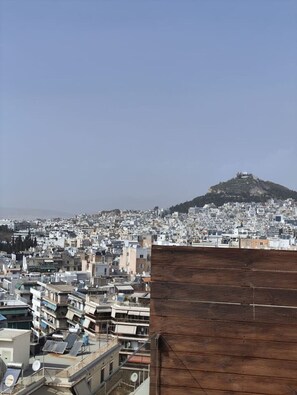 A cityscape with a prominent hill in the background. - Rooftop Serenity in Pangrati | Jacuzzi, 2 Terraces & Acropolis Views in Central Athens (Athina)