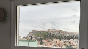 A hotel room with a bed, a window with a view of a historic building and cityscape. - Acropolis View Penthouse | Panoramic Terrace in the Heart of Athens (Athina)
