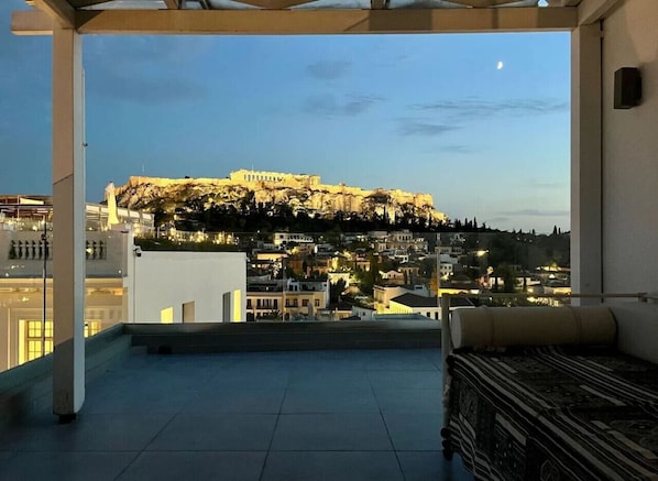 A rooftop terrace with a view of a historic building on a hill.