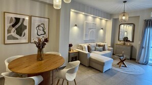 Un salon moderne avec une table de salle à manger ronde en bois, des chaises blanches, un canapé et une table basse.