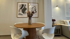 Un espace repas moderne avec une table ronde en bois, des chaises blanches et un vase de fleurs.