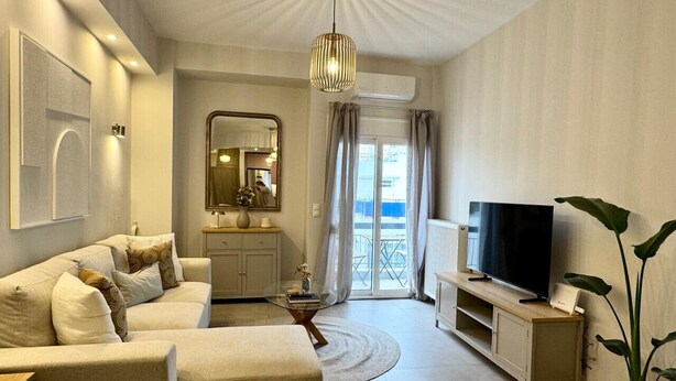 Un salon moderne avec un canapé, un téléviseur, une table basse et une plante en pot.