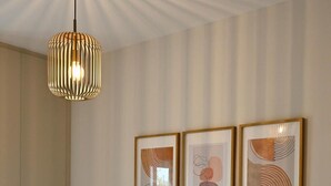 Une chambre avec un grand lit, un luminaire suspendu et trois œuvres d’art encadrées accrochées au mur.