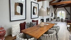 A dining area with a wooden table, cushioned chairs, and framed artwork on the walls. - Grand Amstel Residence | Expansive Two-Story Riverfront Apartment in Central Amsterdam (Amsterdam)