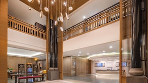Un hall d’entrée spacieux avec un comptoir de réception, un espace salon et un plafond haut orné de luminaires suspendus.