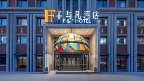 De ingang van Hotel F&F met een kleurrijke glazen koepel en een gevel van baksteen.