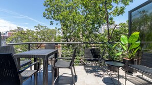 An outdoor patio with wicker furniture, a small round table, and potted plants.