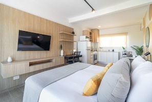 A modern hotel room with a large bed, a flat-screen TV mounted on the wall, a kitchenette, and a small dining area. - Experience Chic & Cozy Rentals in Palermo Soho- 405 (Palermo)