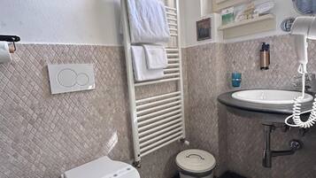 Ein Badezimmer mit Toilette, Handtuchhalter, Waschbecken, Spiegel und Fenster.
