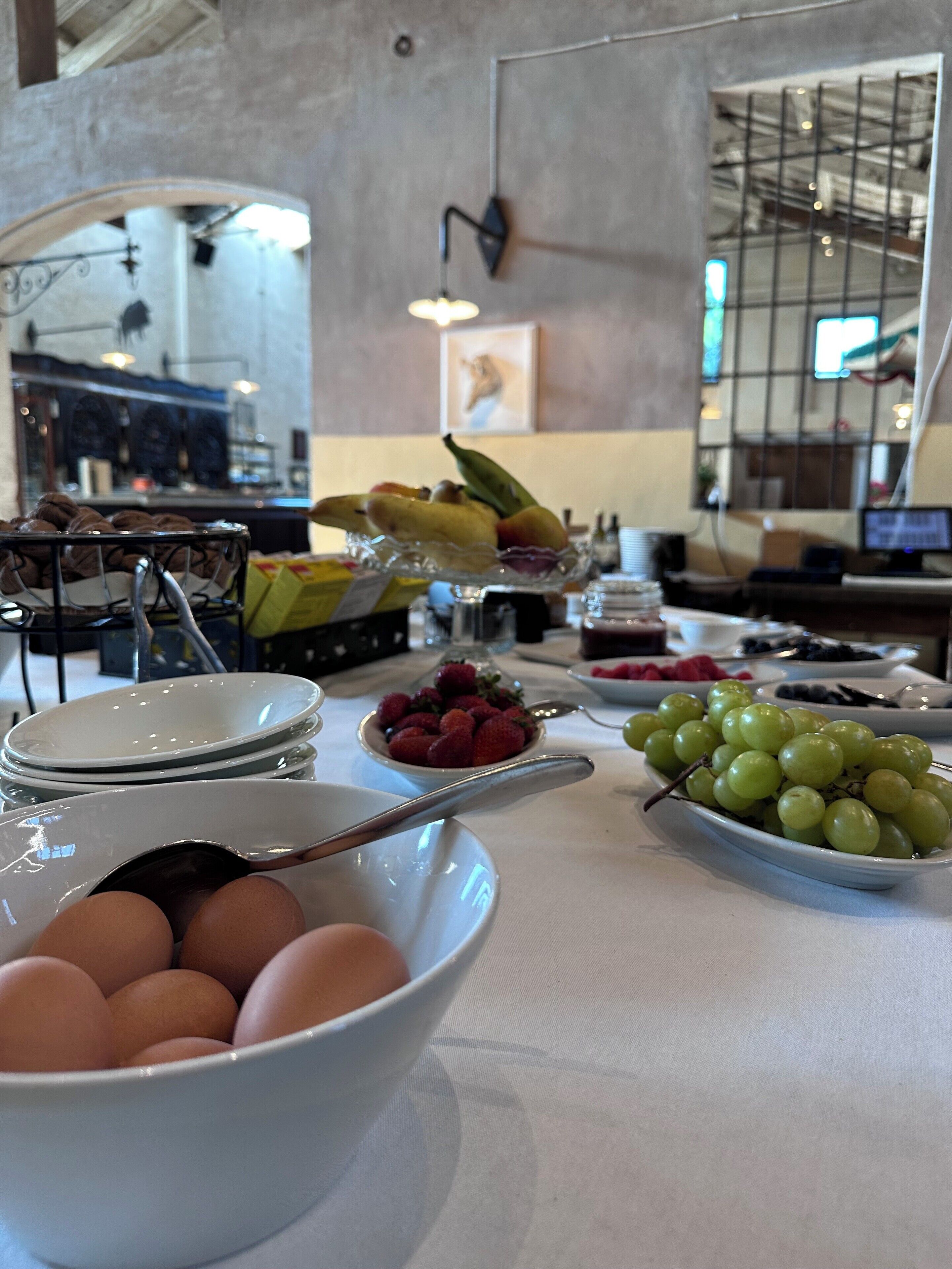 A breakfast buffet with various fruits, eggs, and a coffee station.