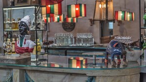 Eine Bar mit einer Glastheke, einer Statue und einer dekorativen Pendelleuchte.