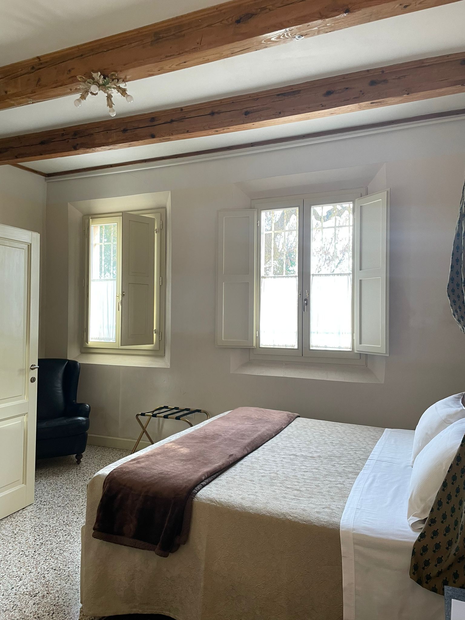 A bedroom with a bed, a chair, a window, and a door.