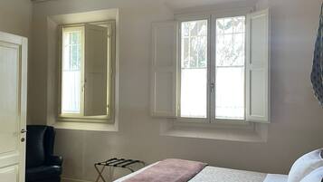A bedroom with a bed, a chair, a window, and a door.