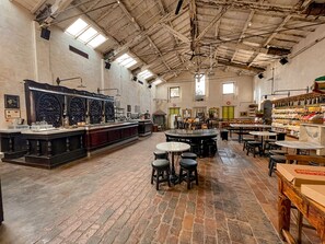A spacious bar area with a long counter, multiple stools, and a variety of bottles and glasses. - Locanda di Casa Spadoni (Faenza)