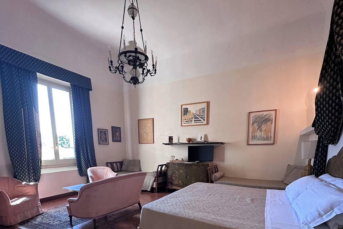 Una habitación de hotel con cama, sofá, escritorio y candelabro.
