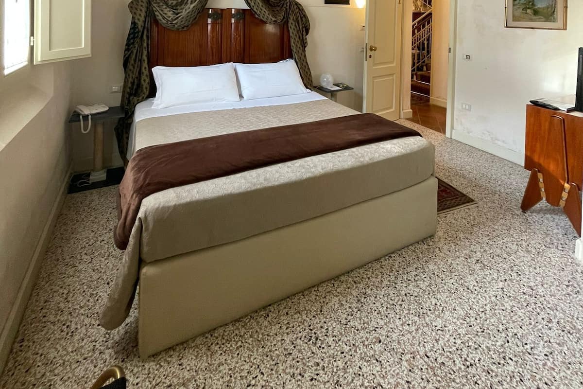 Un dormitorio con techo de madera, una cama con dosel, una mesita de noche, una silla y un escritorio.