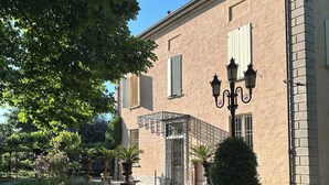 Ein Gebäude mit einer steinernen Fassade, einem verschlossenen Eingang und einem gepflegten Rasen mit Pflanzkübeln.