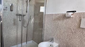 Ett modernt badrum med en dusch med glasväggar, en vit tvättställsbidet och en vit tvättställ.