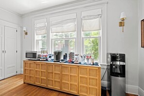 A kitchen with a wooden buffet, a water dispenser, and a microwave.