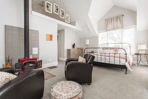 Ein Schlafzimmer mit einem Bett, einem Kamin, einer Couch und einem runden Hocker.