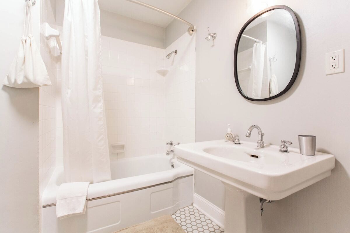 A bathroom with a bathtub, a sink, a mirror, and a shower curtain.
