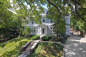 A two-story house with a front porch, a covered entryway, and a driveway leading to a gated entrance.