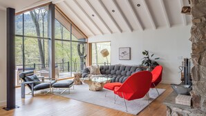 Ein geräumiges Wohnzimmer mit großem Fenster, Steinwand und einer modernen Couch.