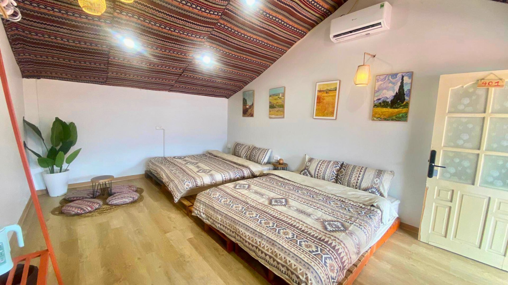 A room with two beds, a potted plant, and a door with frosted glass panels.
