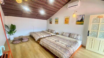 Una habitación con dos camas, una planta en maceta y una puerta con paneles de vidrio esmerilado.