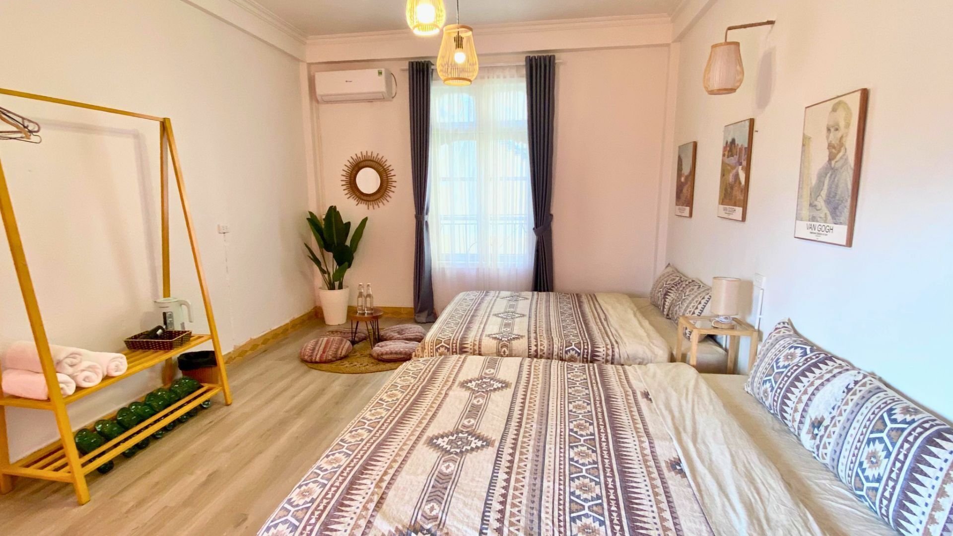 A bedroom with two beds, a hanging chair, a potted plant, and artwork on the walls.