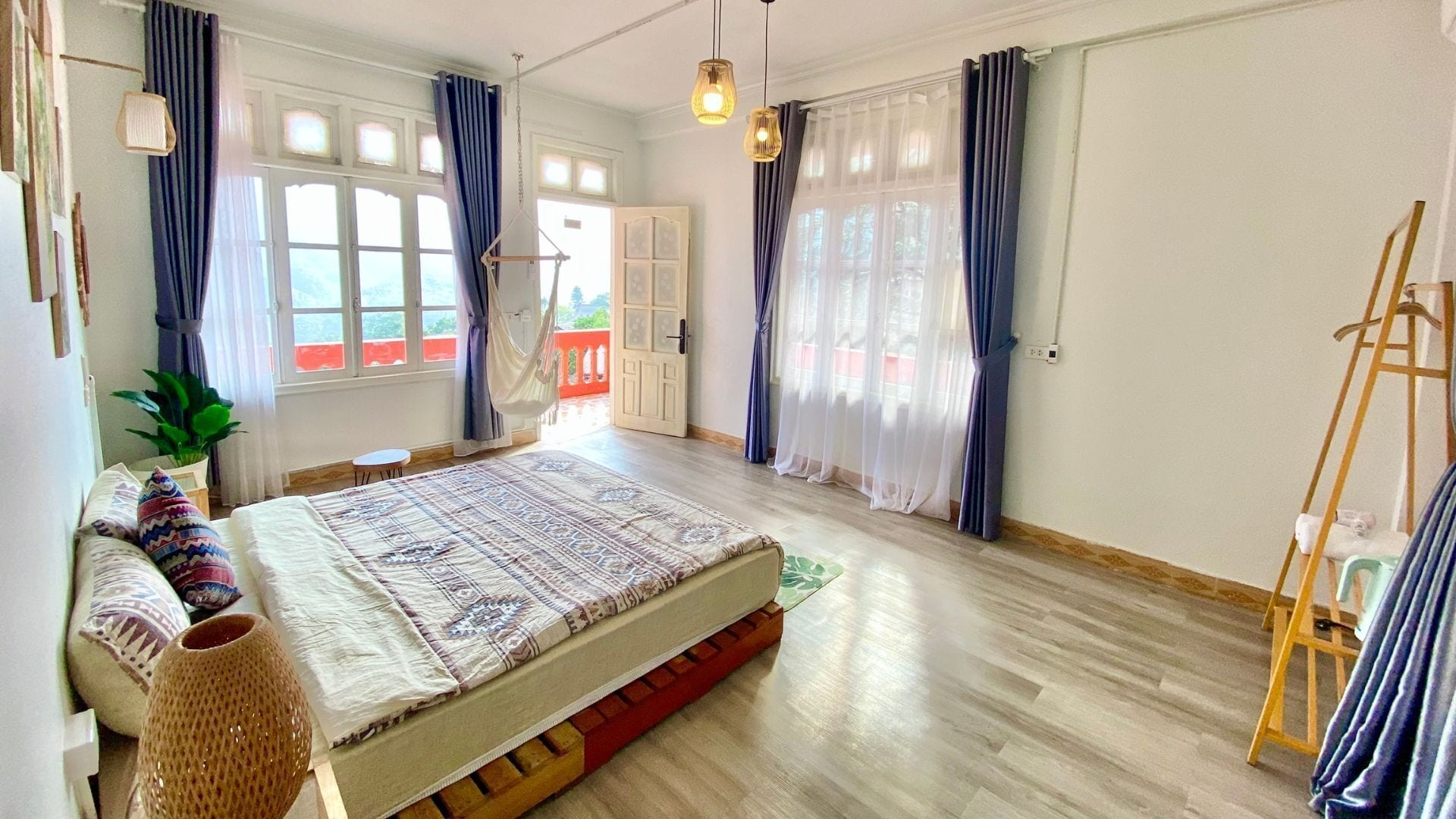A bedroom with a bed, a small table, a hanging chair, and a ladder.