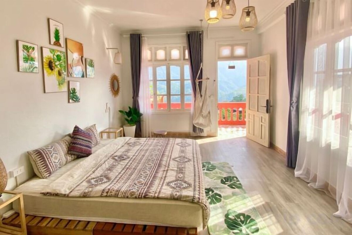 A bedroom with a bed, a window, a door, and a view of the outside.