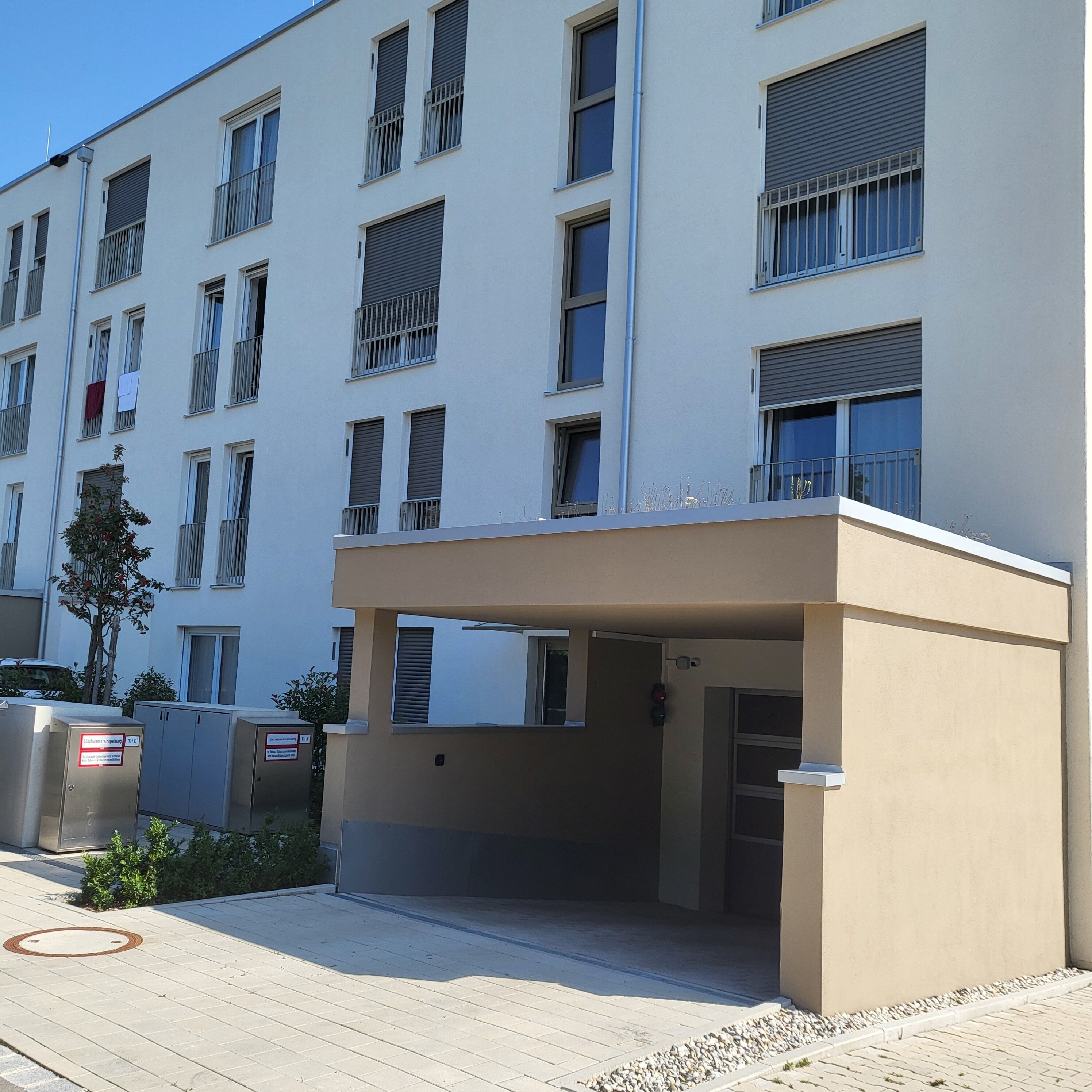 A modern multi-story building with a flat facade, large windows with metal bars, and a gated entrance.