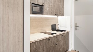 A modern kitchen with a built-in microwave, a sink, and wooden cabinets. - Bader Aparthotel (Unterschleißheim)
