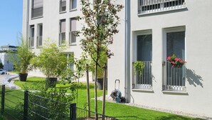 A modern building with multiple windows, a well-maintained lawn, and a metal fence. - Bader Aparthotel (Unterschleißheim)