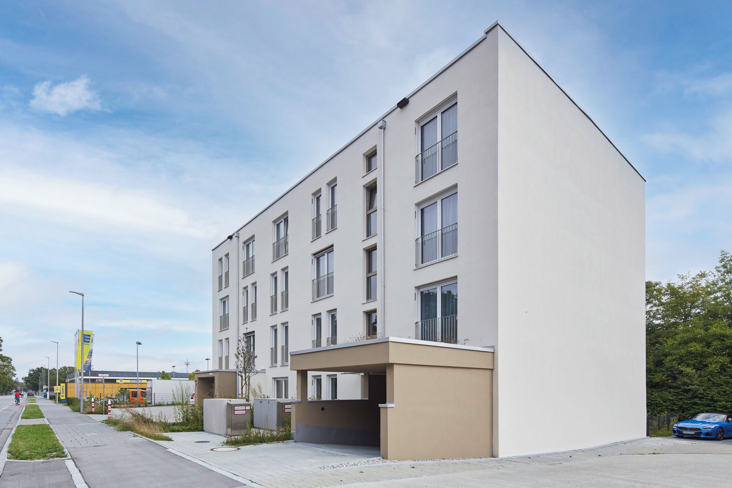 Un edificio moderno con fachada plana, múltiples ventanales y un acceso cubierto.