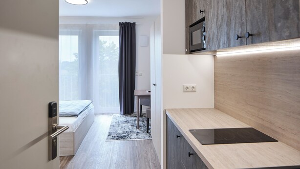 A modern kitchen with a built-in microwave, a wooden countertop, and a black induction cooktop. - Bader Aparthotel (Unterschleißheim)