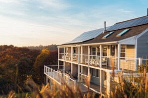A multi-story house with a balcony, solar panels, and a view of trees.