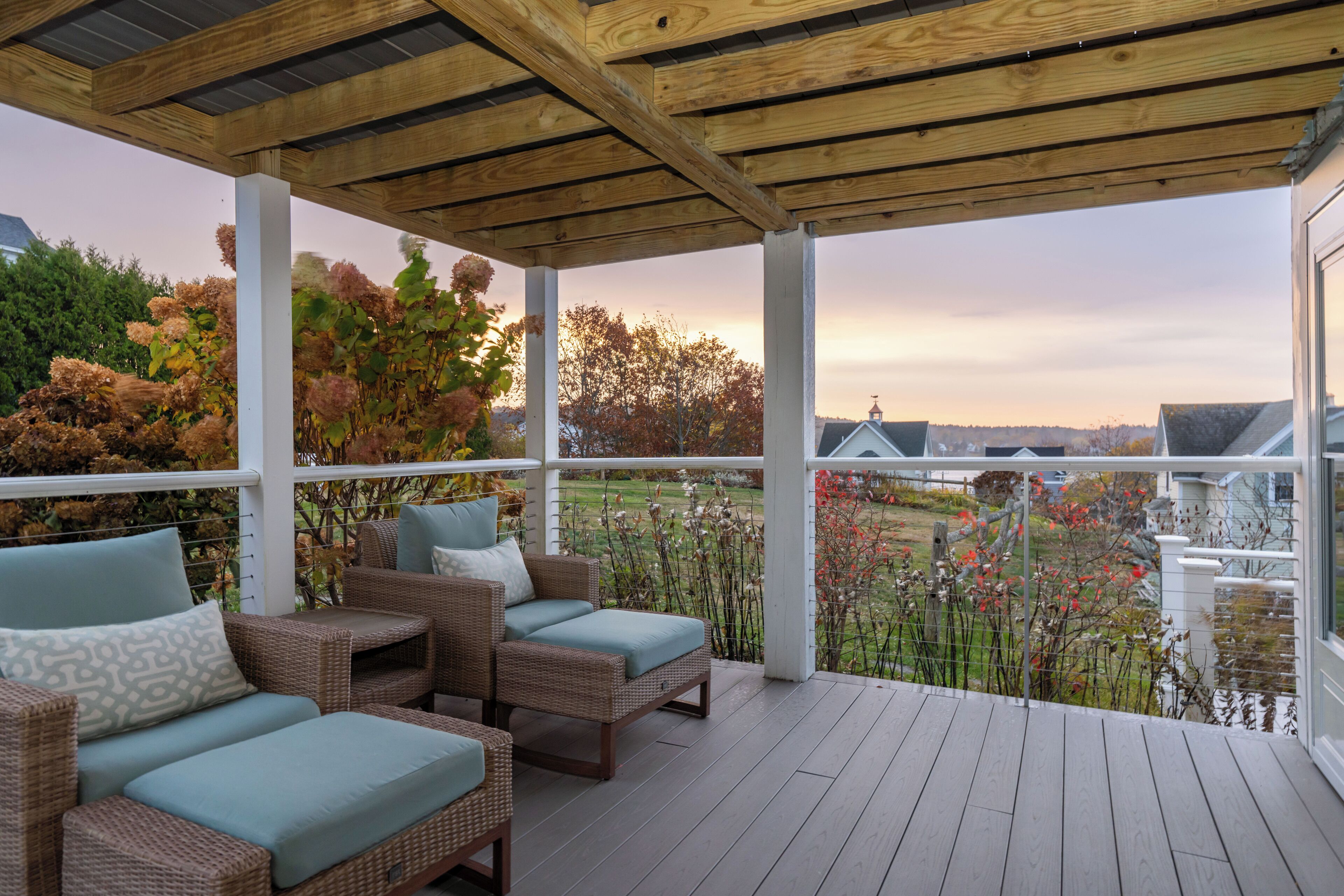 A covered outdoor seating area with wicker furniture and a view of the surrounding landscape.