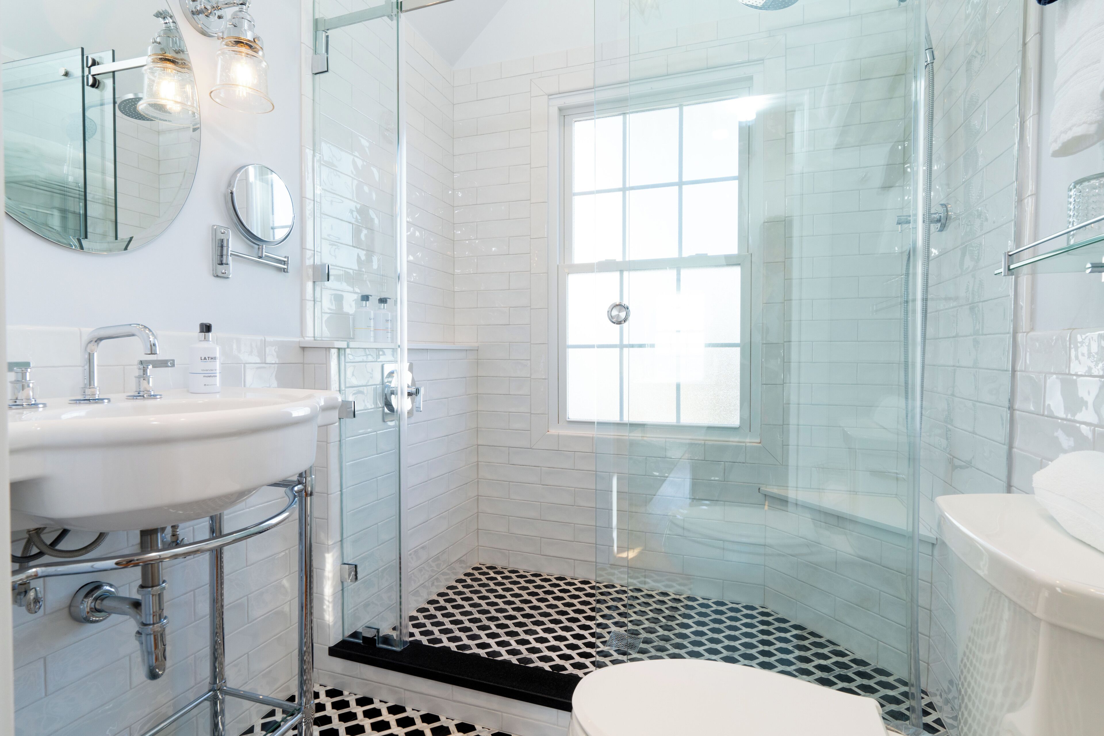 Une salle de bain moderne avec une douche à parois de verre, un lavabo blanc et un grand miroir.