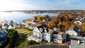 A waterfront property with a large house featuring a front porch, a driveway, and a lawn. - Topside Inn (Boothbay Harbor)